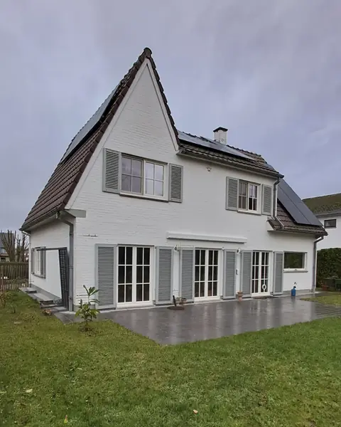 Maison blanche avec panneaux solaires sur deux pans de toiture